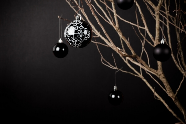 árbol de navidad de tendencia minimalista con bolas de navidad de color negro colgado de una rama sin hojas verdes, sólo madera al natural